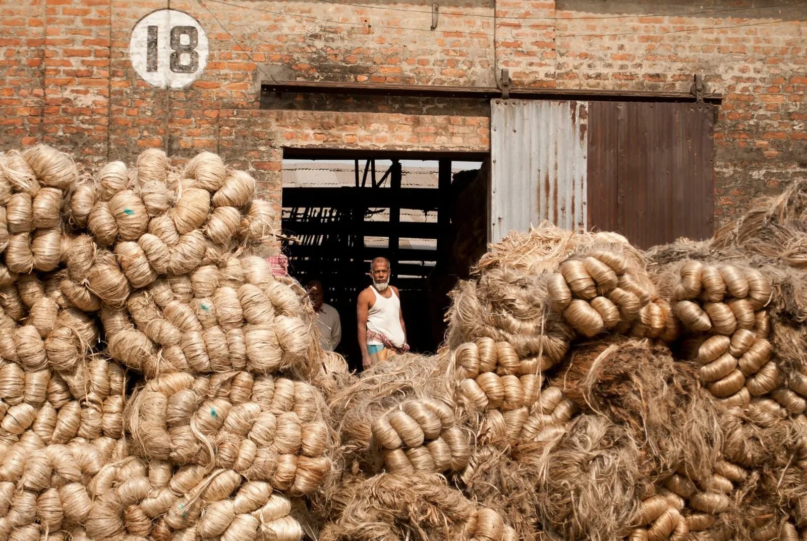 Bales of natural fibre stacked in a warehouse yard