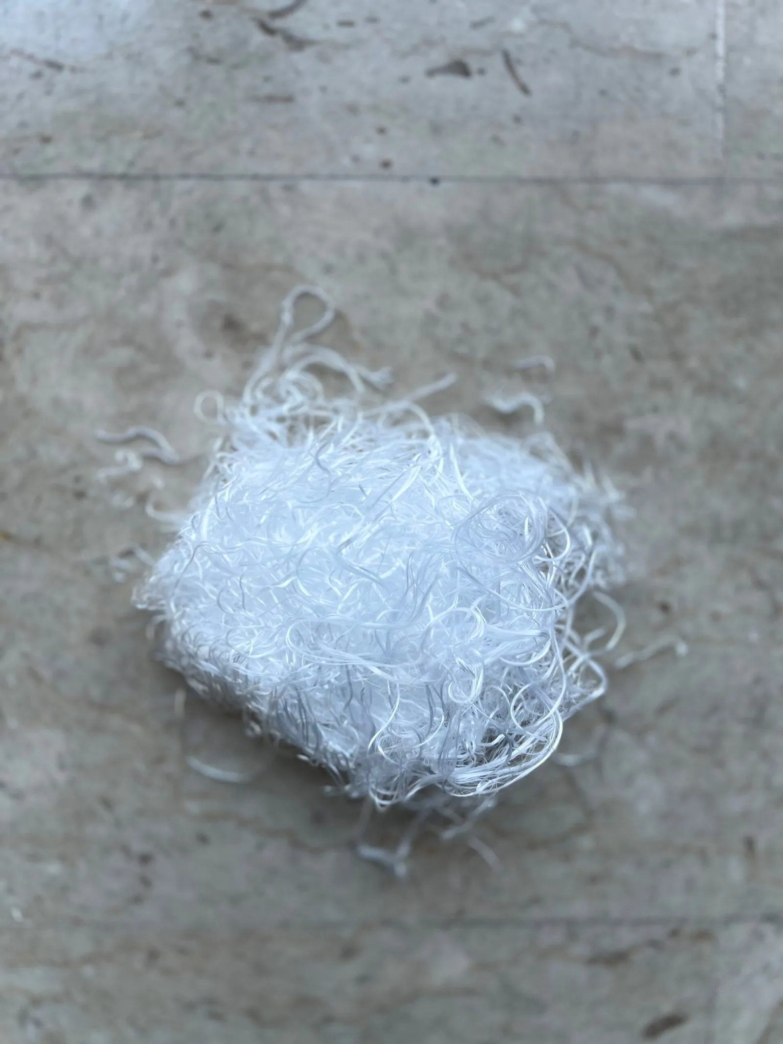 Texturised polyester yarn waste on a stone surface