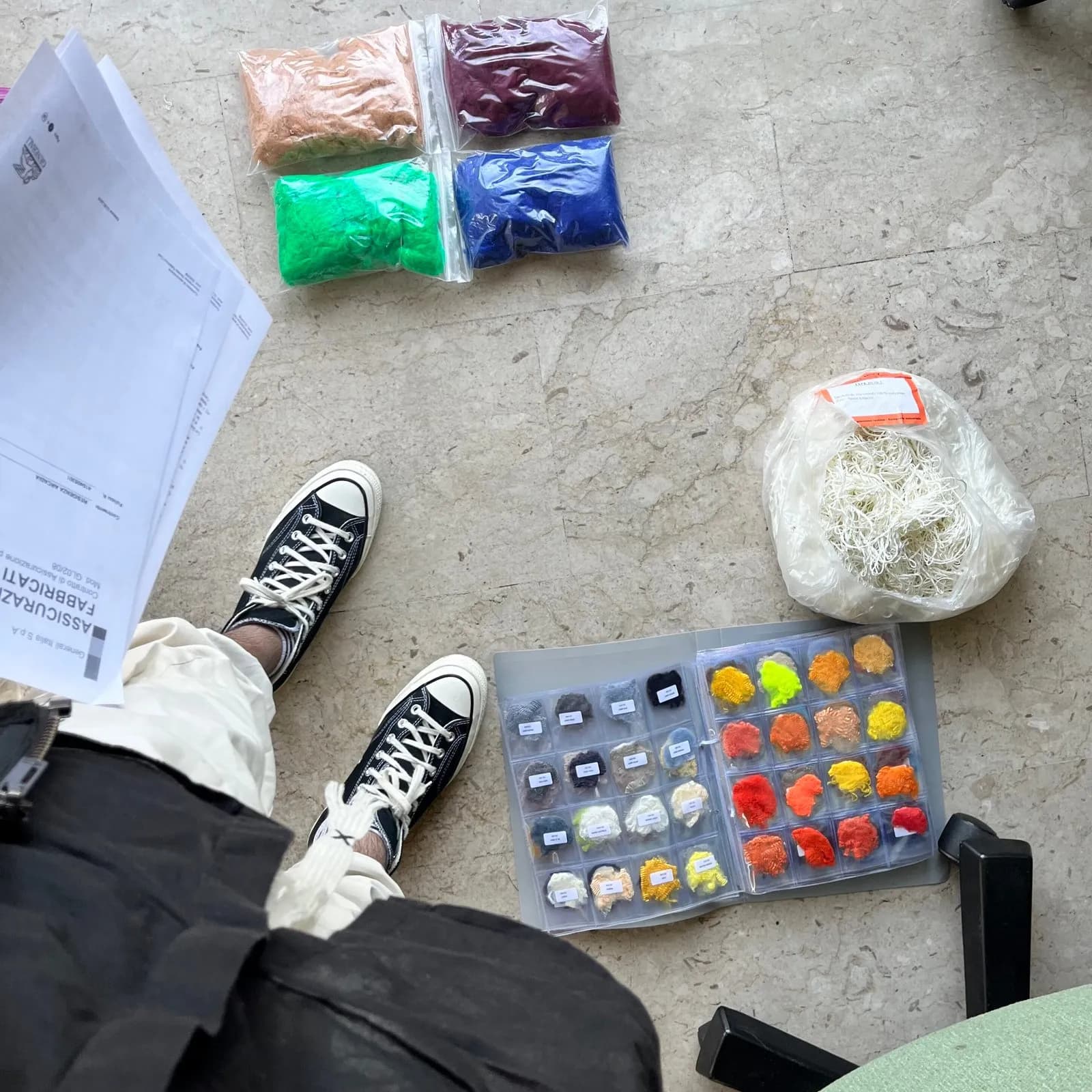 Fibre and fabric samples laid out on the floor with a colour sample tray
