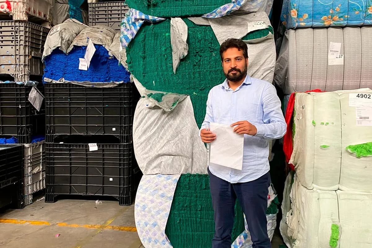 Saifur Rehman, Founder & CEO of EcoFibra, in a warehouse among bales of textile material